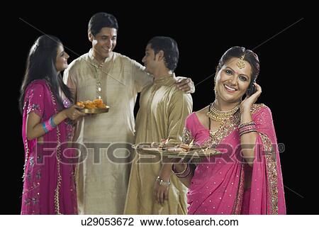 Stock Image - Woman talking on a mobile phone with her family in the background. Fotosearch