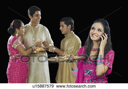 Stock Photo - Woman talking on a mobile phone with her family in the background. Fotosearch