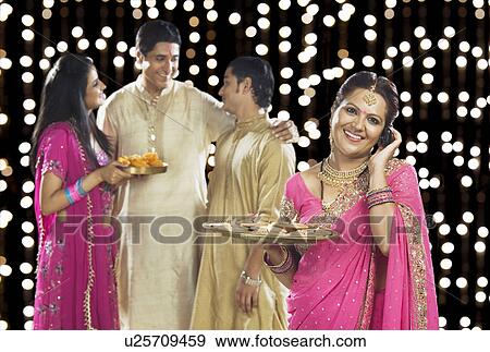 Stock Photo - Woman talking on a mobile phone with her family in the background. Fotosearch