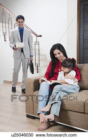 Woman teaching her daughter with her husband holding a gift View Large Photo Image Stock Image - Woman teaching her daughter with her husband holding a gift. Fotosearch