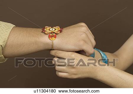 Woman tying rakhi on the wrist of her brother View Large Photo Image Stock Image - Woman tying rakhi on the wrist of her brother. Fotosearch