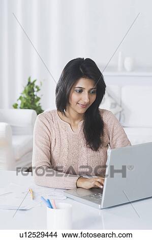 Woman using a laptop at home View Large Photo Image Picture - Woman using a laptop at home. Fotosearch