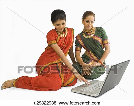 Stock Photo - Woman using a laptop with her friend. Fotosearch