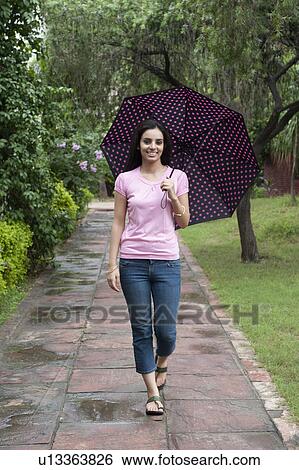 Woman walking in a park with an umbrella View Large Photo Image Stock Photograph - Woman walking in a park with an umbrella. Fotosearch