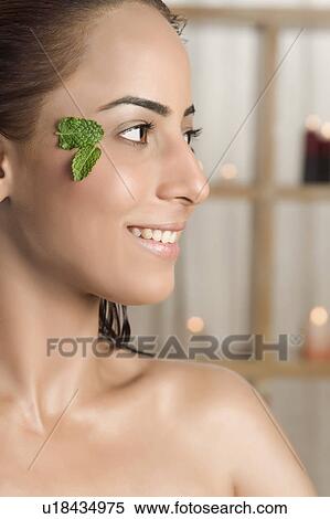Stock Photography - Woman with a leaf on her face smiling in health spa. Fotosearch