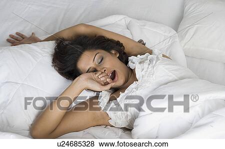 Stock Photo - Woman yawning on the bed. Fotosearch