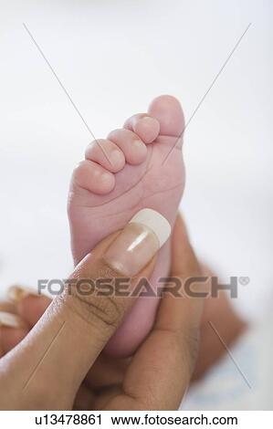 Stock Image - Woman's hand touching baby's feet. Fotosearch