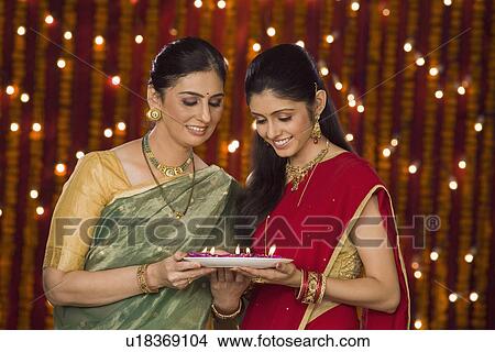 Women holding an oil lamp and smiling View Large Photo Image Picture - Women holding an oil lamp and smiling. Fotosearch