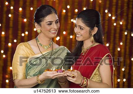 Women holding an oil lamp and smiling View Large Photo Image Stock Image - Women holding an oil lamp and smiling. Fotosearch