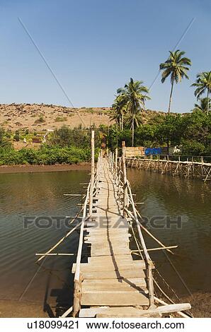 Stock Image - Wooden bridge across the river, Goa, India. Fotosearch