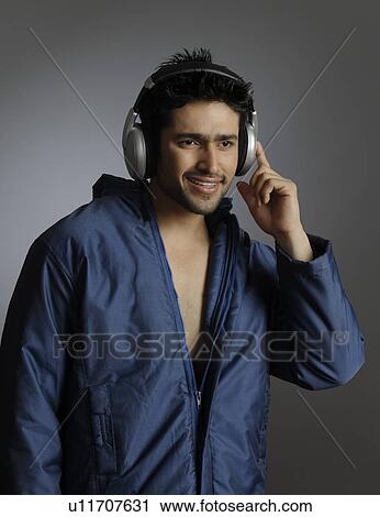 Stock Image - Young man listening to music with headphones. Fotosearch