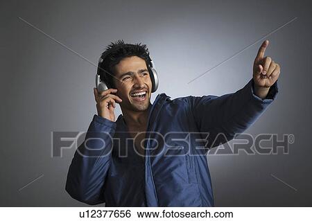 Young man listening to music with headphones View Large Photo Image Stock Photograph - Young man listening to music with headphones. Fotosearch
