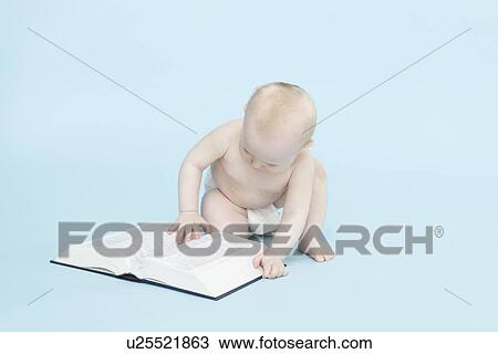 Stock Image - Baby boy playing with book. Fotosearch