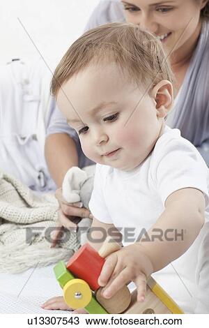 Stock Image - Baby playing with wooden train. Fotosearch