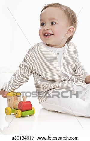 Stock Photo - Baby playing with wooden train. Fotosearch
