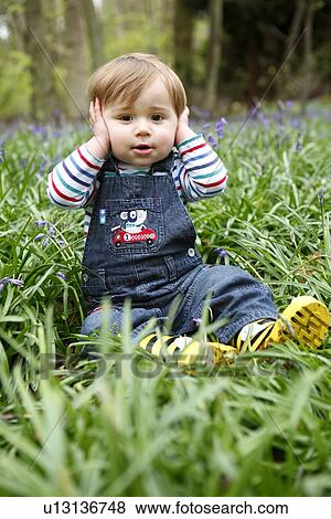 Boy covering his ears in meadow View Large Photo Image Stock Photo - Boy covering his ears in meadow. Fotosearch