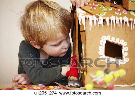 Picture - Boy decorating gingerbread house. Fotosearch