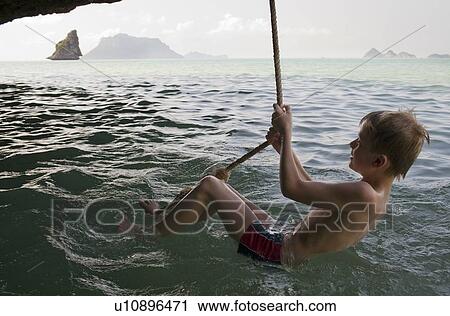Boy playing on rope over water View Large Photo Image Stock Image - Boy playing on rope over water. Fotosearch