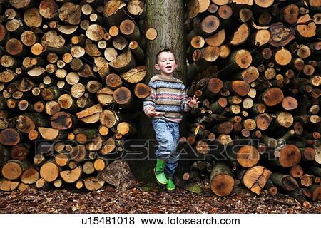 Boy standing by logs of wood View Large Photo Image Stock Photo - Boy standing by logs of wood . Fotosearch
