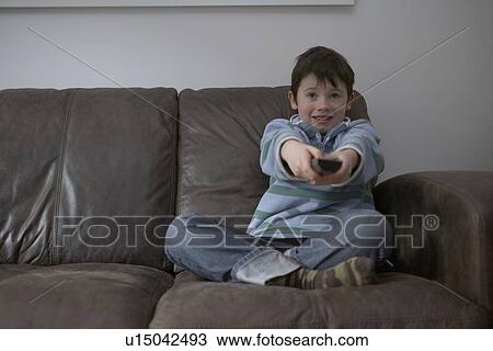 Boy watching television in living room View Large Photo Image Stock Image - Boy watching television in living room. Fotosearch