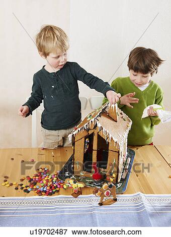 Stock Photo - Boys decorating gingerbread house. Fotosearch