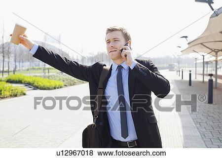 Stock Photo - Businessman hailing taxi on city street. Fotosearch
