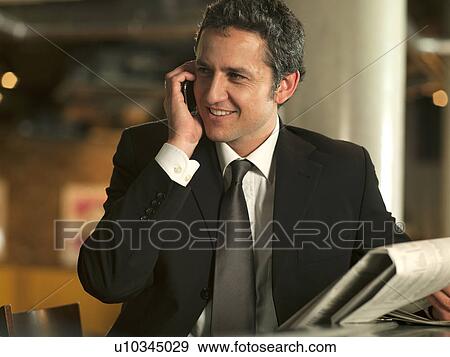 Stock Photo - Businessman on cell phone in cafe. Fotosearch