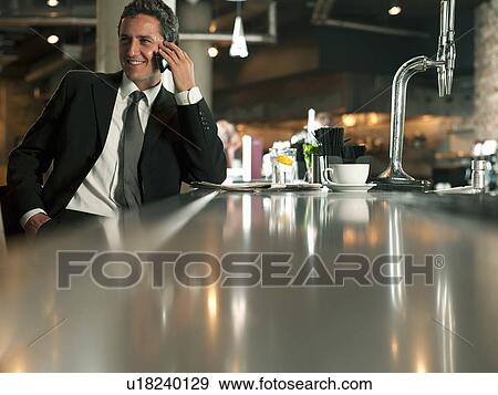 Stock Photo - Businessman on cell phone in cafe. Fotosearch