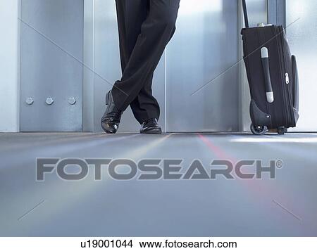 Picture - Businessman standing with luggage. Fotosearch