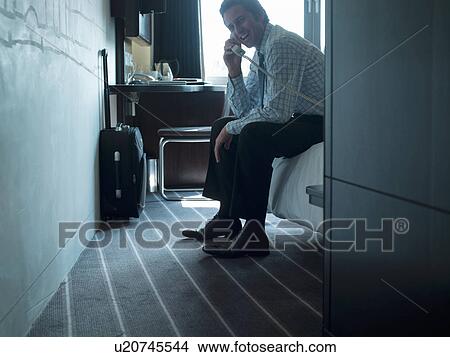 Picture - Businessman talking on phone in hotel. Fotosearch