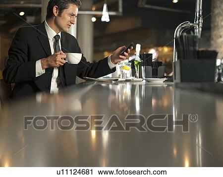 Businessman using cell phone in cafe View Large Photo Image Stock Image - Businessman using cell phone in cafe. Fotosearch