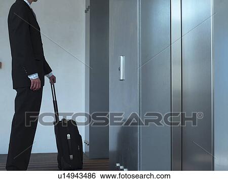 Businessman with luggage at elevator View Large Photo Image Stock Photograph - Businessman with luggage at elevator. Fotosearch