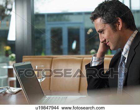 Picture - Businessman working on laptop in cafe. Fotosearch