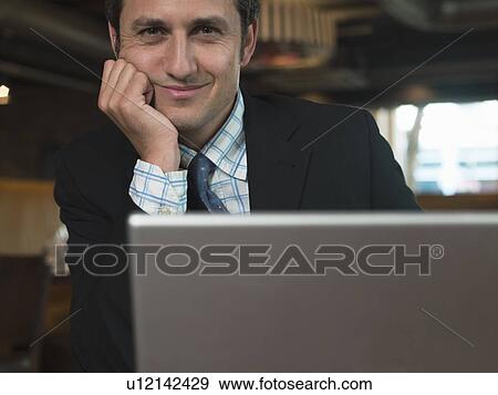 Businessman working on laptop in cafe View Large Photo Image Stock Photo - Businessman working on laptop in cafe. Fotosearch