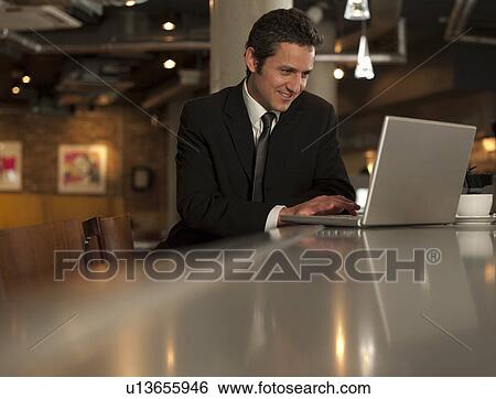 Stock Photograph - Businessman working on laptop in cafe. Fotosearch