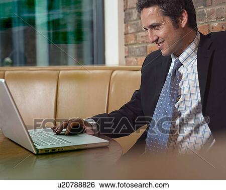Businessman working on laptop in cafe View Large Photo Image Stock Photograph - Businessman working on laptop in cafe. Fotosearch