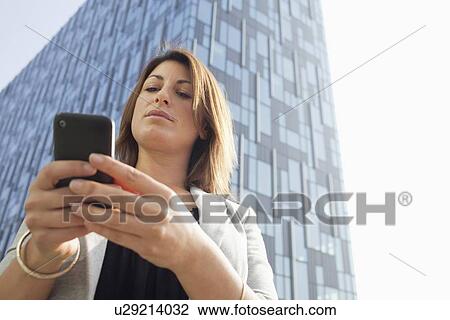 Stock Image - Businesspeople using cell phone outdoors. Fotosearch