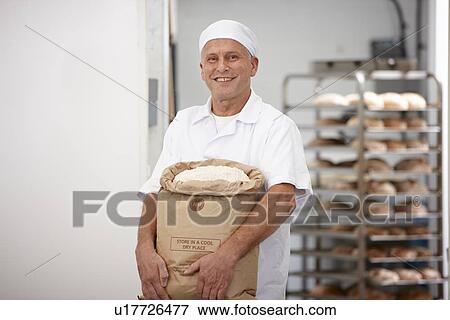 Stock Photo - Chef carrying sack of flour in kitchen. Fotosearch