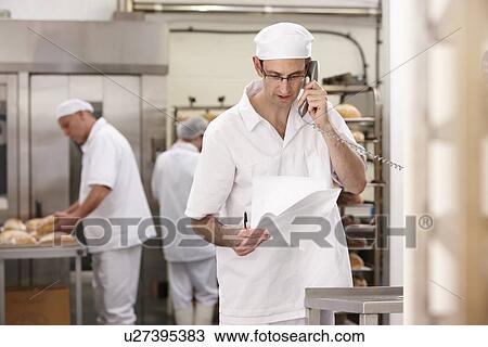 Stock Image - Chef talking on phone in kitchen. Fotosearch