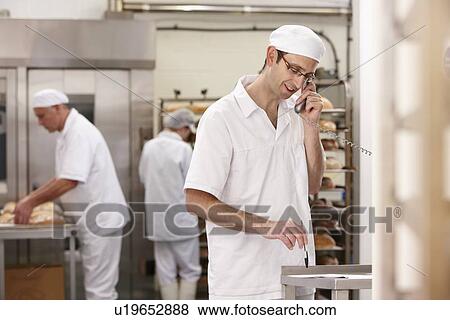 Stock Photo - Chef talking on phone in kitchen. Fotosearch