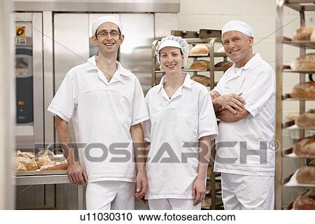 Stock Image - Chefs smiling together in kitchen. Fotosearch