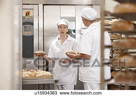 Stock Image - Chefs talking at oven in kitchen. Fotosearch