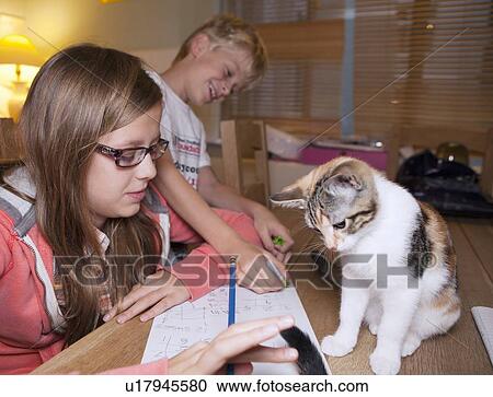 Stock Image - Children with cat during homework. Fotosearch
