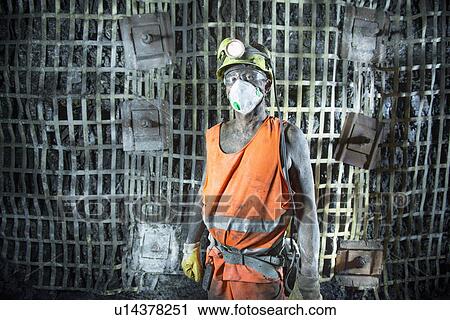 Stock Image - Coal miner standing in mine. Fotosearch
