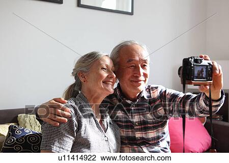 Stock Image - Couple taking pictures of themselves. Fotosearch