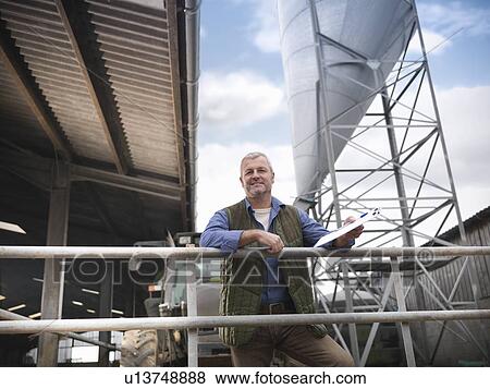 Stock Photo - Farmer standing outside barn. Fotosearch