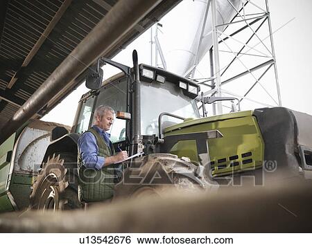 Farmer writing notes by tractor View Large Photo Image Stock Photograph - Farmer writing notes by tractor. Fotosearch