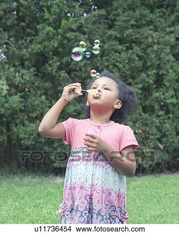 Girl blowing bubbles outdoors View Large Photo Image Picture - Girl blowing bubbles outdoors. Fotosearch