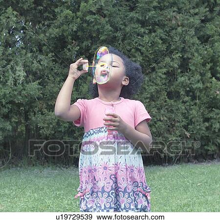 Stock Photo - Girl blowing bubbles outdoors. Fotosearch
