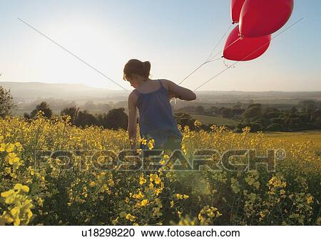 Girl carrying balloons in field View Large Photo Image Stock Image - Girl carrying balloons in field. Fotosearch